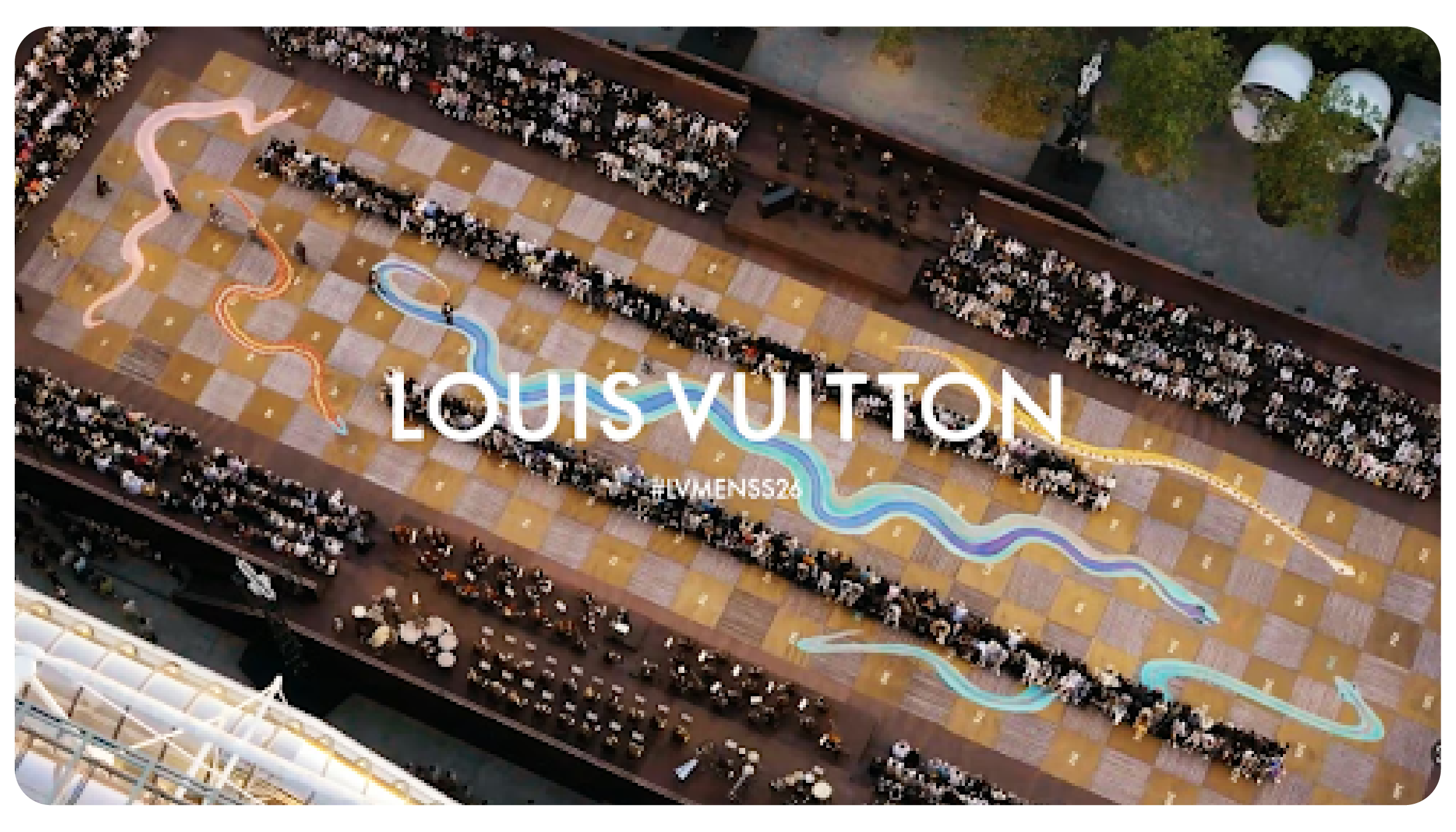 An aerial view of the Louis Vuitton Men's Spring-Summer 2026 fashion show, featuring a massive checkerboard runway with colorful, winding paths and guests seated for the event.