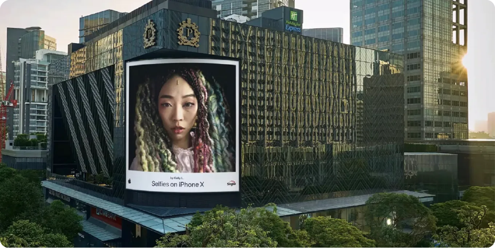 An Apple #ShotOniPhone billboard on a city building, showcasing a user's photo as a powerful example of a user-generated content (UGC) campaign in digital branding.